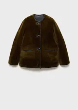 Chaqueta beige de poliéster con textura de borreguito, cuello redondo, cierre frontal con botones tipo trenca, ribetes en contraste de color negro, dos bolsillos delanteros y forro interior.