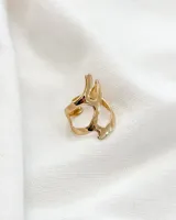Anillo dorado con diseño abstracto y abertura ajustable.