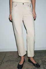 Jeans de tiro medio color beige, corte cigarette, con cinco bolsillos y cierre frontal de cremallera y botón.