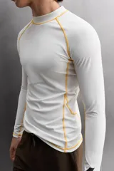Camiseta de surf compresiva slim fit confeccionada en tejido técnico muy elástico y ligero. Con factor de protección ultravioleta 40+, cuello subido, manga larga, costuras planas y acabados combinados a contraste.