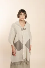 Chal de lana fina sin teñir, con calce en hombros, abrochadura con alamar de fieltro, bolsillos de cuero y terminación con flecos. Diseño exclusivo de Don Baez, hecho en Uruguay.