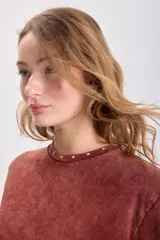 Remera color terracota con cuello redondo y estrellas bordadas alrededor del cuello.