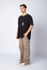 Remera negra de corte holgado con cuello y mangas con ribete verde. Bolsillo en el pecho con estampado de sello postal.