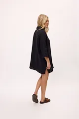 Vestido camisero a rayas verticales de colores pastel, con cuello camisero, cierre frontal con botones y mangas largas.