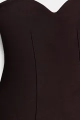 Top color crema o blanco roto, sin mangas, con escote corazón y corte ajustado al cuerpo con un ligero vuelo en el bajo.