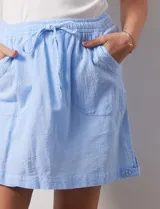 Falda short de algodón a rayas verticales en tonos celeste, azul y blanco. Cuenta con pretina elastizada con cordón de ajuste, bolsillos laterales y short interno.