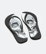 Chinelas negras con base blanca y estampado de calaveras en blanco y negro. Las tiras son negras con diseño geométrico en relieve.