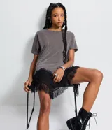 Remera de algodón color gris desteñido, con recortes asimétricos, mangas cortas y bajo irregular con encaje negro.