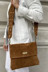 Bandolera marrón de cuero gamuzado, con correa extensible con tachas y arandelas. Tiene forro y bolsillo interno con cierre. La solapa tiene un imán para cerrar con mayor seguridad.