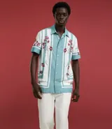 Pantalón de vestir blanco, de corte recto, con bolsillos laterales y traseros. Se ajusta a la cintura con cinturón de cuero marrón.