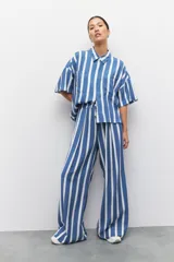 Pantalón largo azul con rayas verticales blancas, de corte amplio, con cintura elastizada y cordón ajustable.
