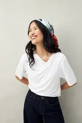 Remera de modal color marrón claro, de manga corta, con cuello asimétrico y detalle de nudo con frunces.