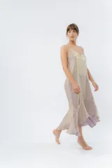 Vestido midi color lila metálico de breteles finos regulables, escote en V y ruedo asimétrico con leve vuelo.