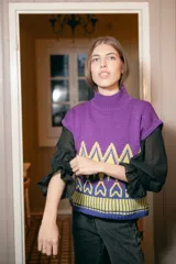 Chaleco de punto morado con cuello alto y diseño geométrico amarillo y azul.