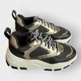 Zapatillas deportivas color beige con cordones a rayas en blanco y negro, suela de goma con plataforma y diseño chunky.