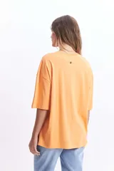 Remera naranja de corte amplio con estampado de flores blancas.