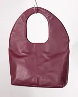 Bolso tote negro de cuero con manija circular rígida.