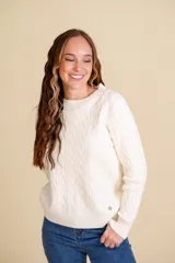 Buzo tejido básico color blanco con diseño de trenzado en la misma tela, ajuste al cuerpo, y cuello redondo.