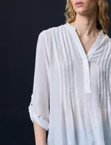 Blusa blanca de gasa bambula, marca Zac & Rachel. Cuello a la base, escote en V con apertura y botones. Largo de manga regulable con presilla y botón.
