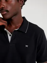 Camisa polo color rosa claro con cuello clásico, tapeta de dos botones y bordado de logo en el pecho. Presenta ribete azul marino en cuello y mangas. Corte clásico.