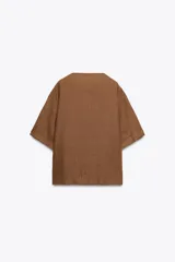 Blusa color marrón confeccionada en lino 100%, de corte holgado, cuello redondo, manga corta y bolsillo de parche en el pecho.