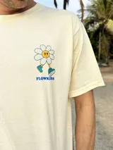 Remera beige de algodón con estampa en la espalda de una flor sonriente sobre un fondo a cuadros azules y texto "FLOWKERS".