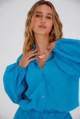 Conjunto turquesa símil lino, compuesto por una camisa de manga globo con botones y un short con cintura elastizada.