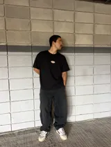 Remera negra de corte boxy con parche ovalado con texto en el frente.