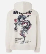 Hoodie color beige claro, corte boxy, con capucha ajustable y bolsillo canguro. Presenta un gran estampado gráfico en la espalda con un dragón oriental, texto en inglés y caracteres japoneses, y la palabra "BRAVE" en la parte superior.