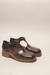 Zapato guillermina de cuero vacuno charol color negro, con suela de goma color marrón.