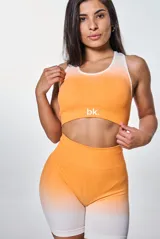 Conjunto deportivo de calza corta y top, color naranja con degradado a blanco. El top es de corte deportivo con logo "bk." en el frente.