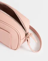 Bandolera color rosa viejo de cuerina, con bolsillo frontal, correa larga regulable y tag metálico.