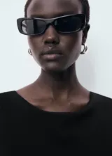 Vestido midi negro de corte ajustado, con cuello barco y espalda descubierta.