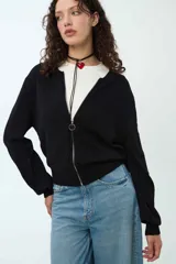 Buzo blanco de punto con cierre frontal y cuello redondo, diseño ajustado.