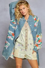 Camisa oversize de denim con detalles patchwork florales, cuello clásico, botones frontales y bordes deshilachados estilo boho.