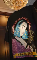 Remera negra de manga corta y cuello redondo, con calce oversize. Presenta una estampa sublimada inspirada en el tarot, con la imagen de una mujer de cabello azul con estrellas, tres espadas y rosas moradas, y la frase "3 DE ESPADAS" en una cinta.