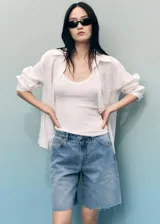 Short de jean azul de tiro medio con cierre de cremallera y botón, cinco bolsillos, diseño recto y bajo deshilachado.