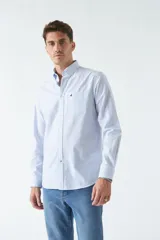 Camisa oxford celeste con rayas verticales blancas, de manga larga y corte regular. Tiene cuello abotonado, bolsillo en el pecho y logo bordado.