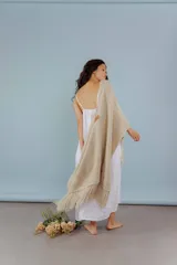 Ruana de lana merino color beige, tejida a mano con detalles de brillos y flecos.