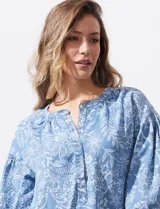 Blusa celeste con estampado floral blanco, escote en V y botones. Mangas 3/4 abullonadas con terminación elastizada.