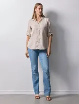 Camisa color beige de tencel, marca Hester & Orchand. Cuello con solapa, escote en V y abertura central con botones. Delantera con bolsillos. Largo de manga regulable con presilla y botón.