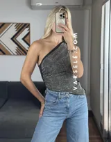 Top asimétrico negro con un solo tirante y detalle de strass plateados.