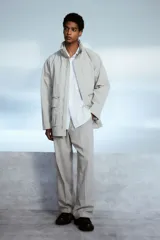 Camisa blanca de popelina de algodón con cuello inglés, tapeta clásica, dos bolsillos superiores abiertos, canesú con pliegue de caja en la espalda, mangas largas con puños abotonados, tapeta de manga con botón y bajo levemente redondeado. Corte holgado.