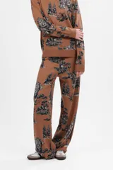 Pantalón largo color camel con estampado de paisaje en tonos negros y grises.