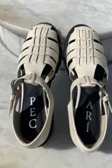 Sandalias de cuero color cobre con diseño de tiras entrecruzadas, hebilla lateral y suela track color negro.