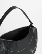 Bandolera negra con forma de media luna, asa corta de hombro y costura decorativa blanca con diseño de ondas y corazón.