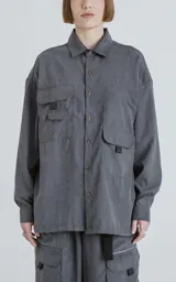 Camisa de manga larga color grafito, estilo técnico con múltiples bolsillos delanteros con tapa y botones en cartera y puños. Presenta un calce oversize y está confeccionada en textil ligero y suave al tacto.