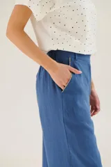 Pantalón de lino azul de corte palazzo con botón decorativo en la cintura.