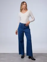 Jean de tiro alto y pierna ancha, color azul denim. Cuenta con pretina con pasadores, botón y cierre. Tiene bolsillos traseros y terminación de ruedo desflecado.