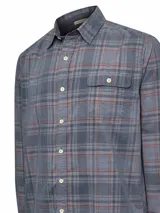 Camisa de franela de algodón orgánico a cuadros en tonos azul, gris y verde. Tiene cuello camisero, manga larga, un bolsillo en el pecho y cierre con botones.